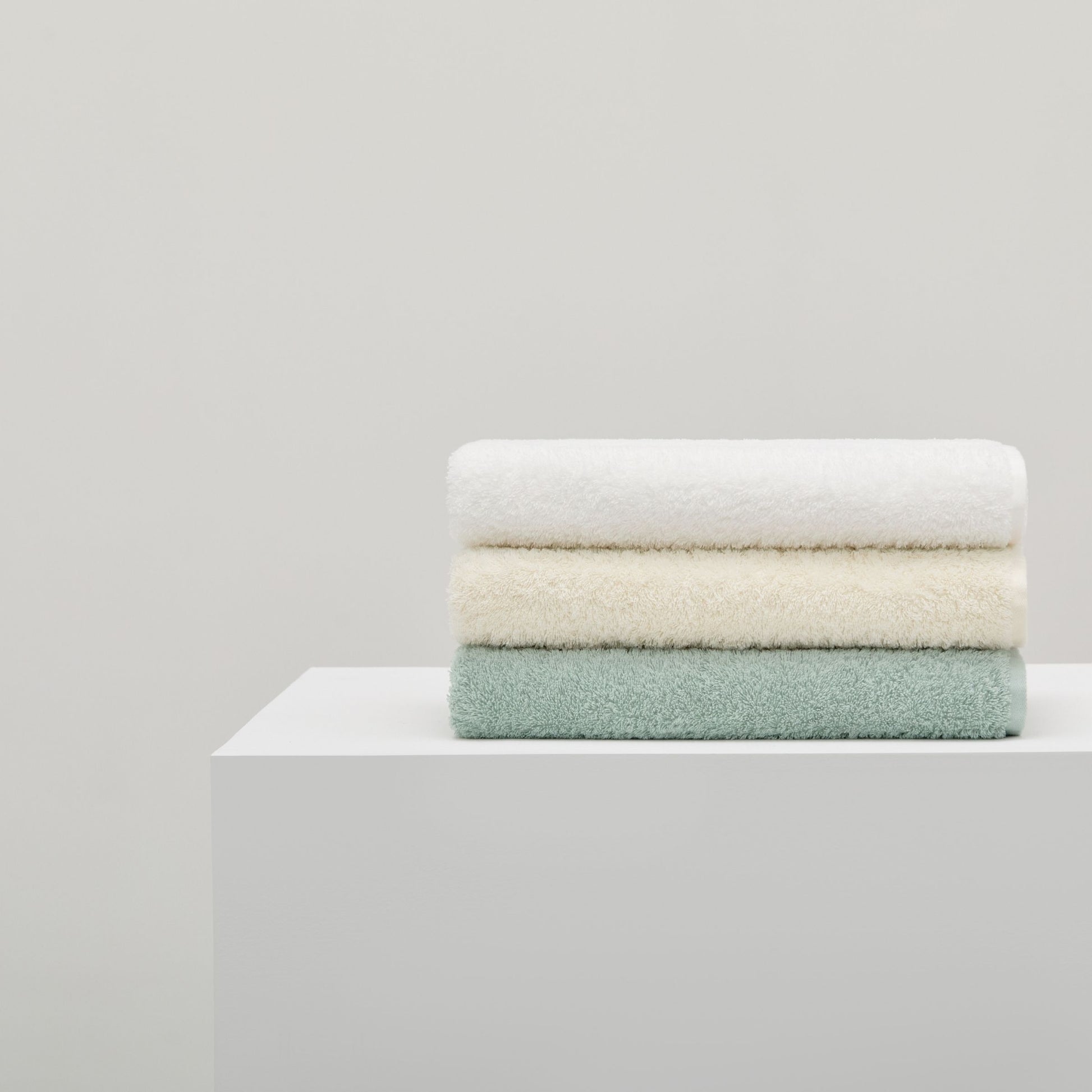 Stack of folded towels in white, beige, and green
