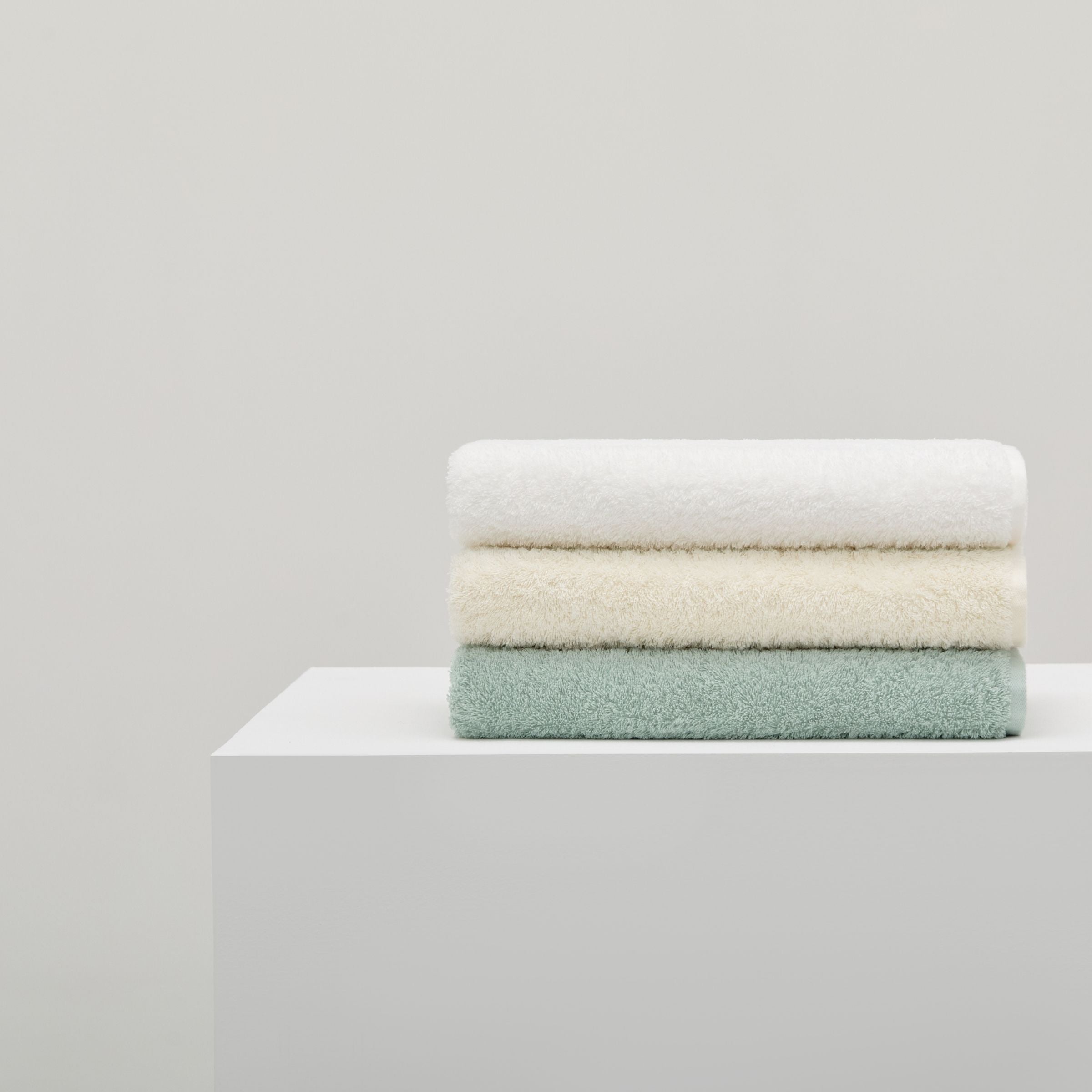 Stack of folded towels in white, beige, and green