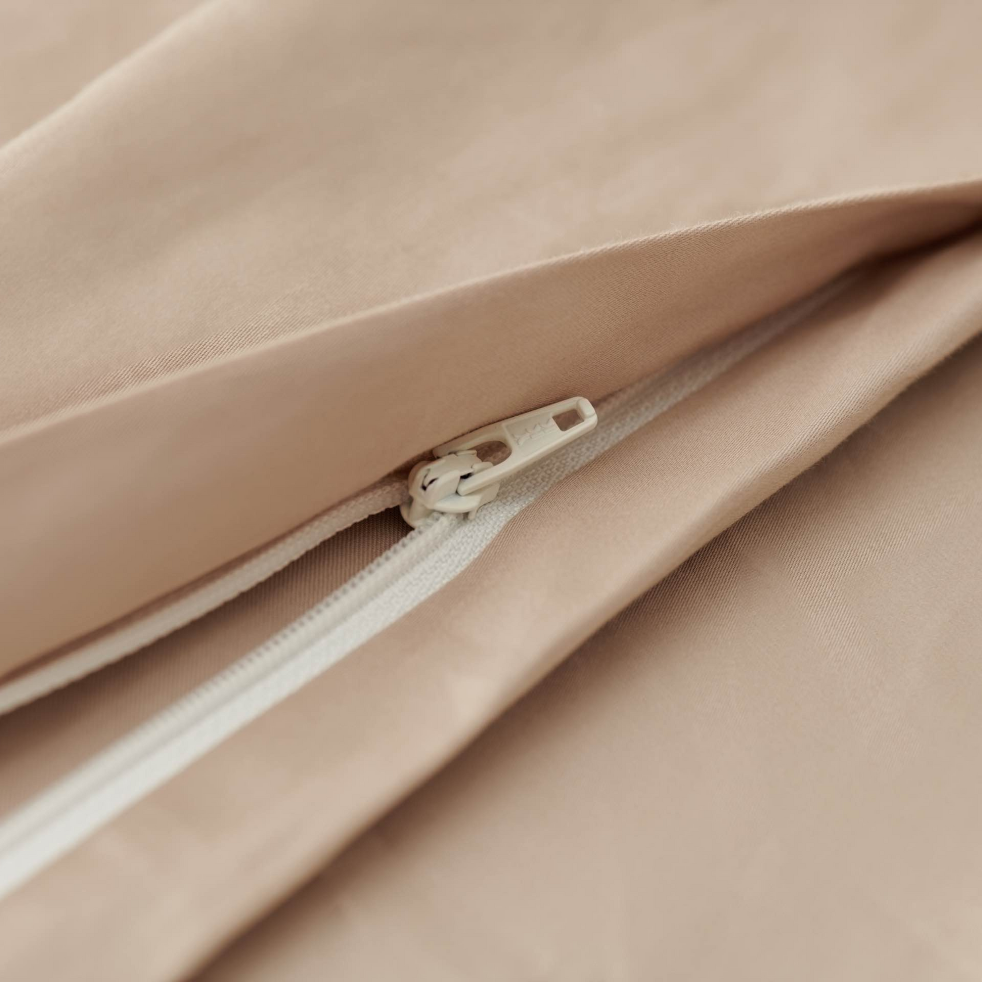 Close-up of a beige cotton duvet cover with a zipper and button detail