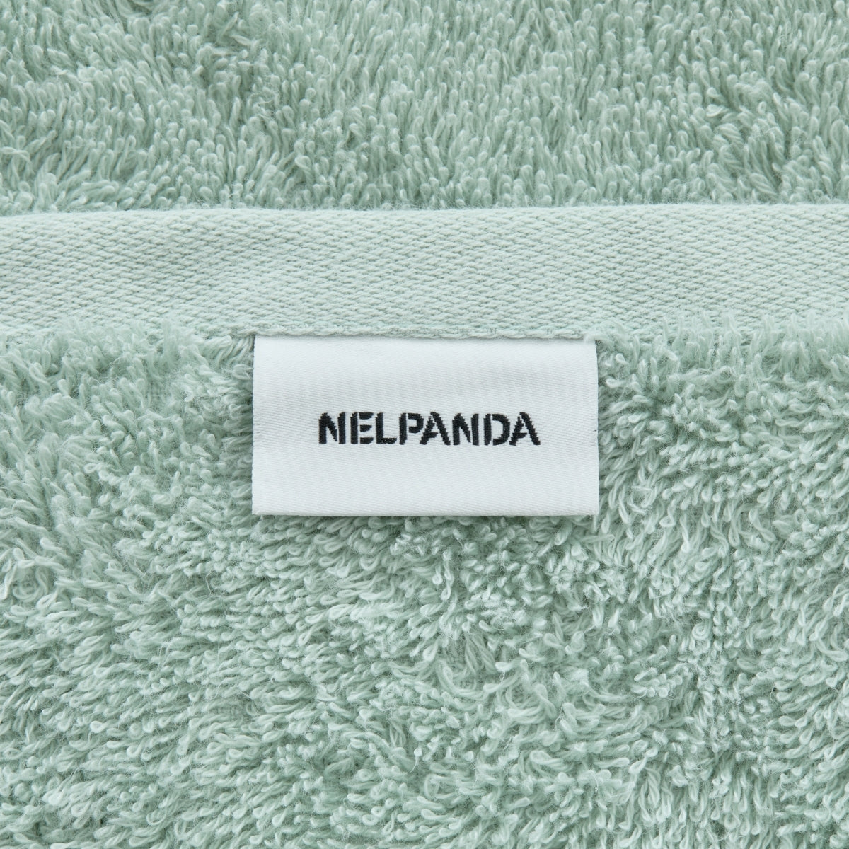 Green towel with a white label displaying 'NIELPANDA' on a textured fabric background.
