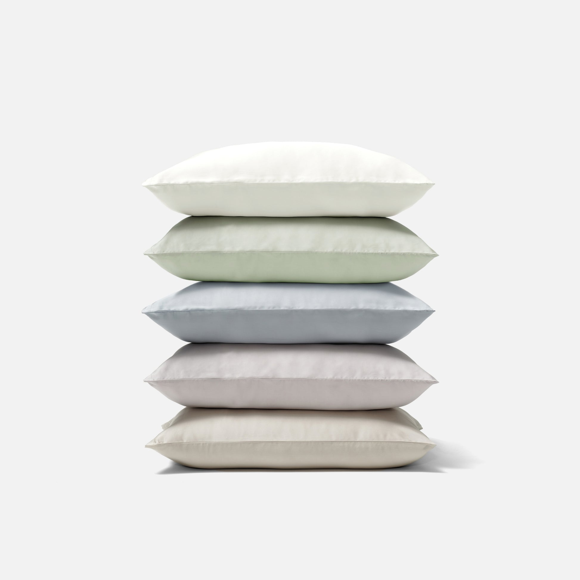 Stack of five soft pillows in various neutral colors