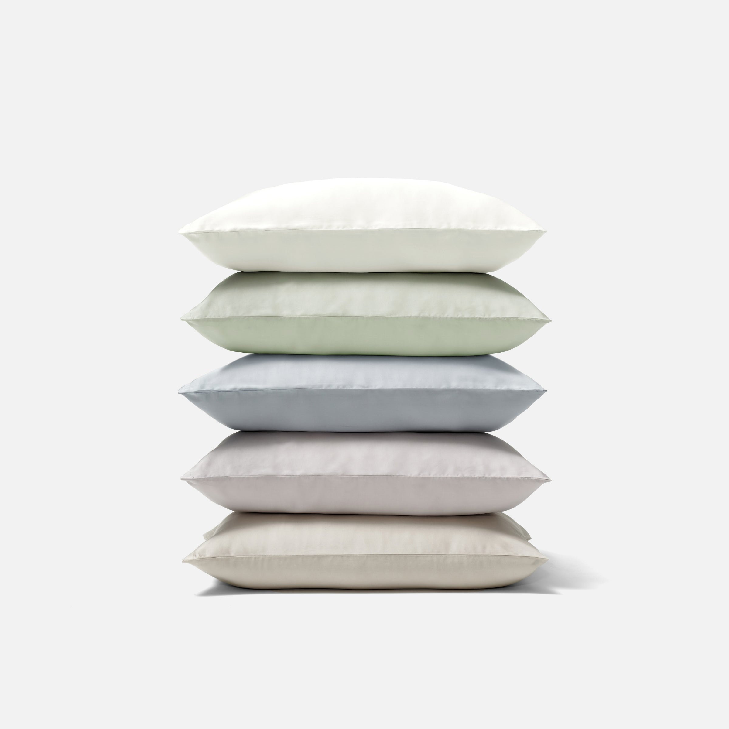 Stack of five soft pillows in various neutral colors