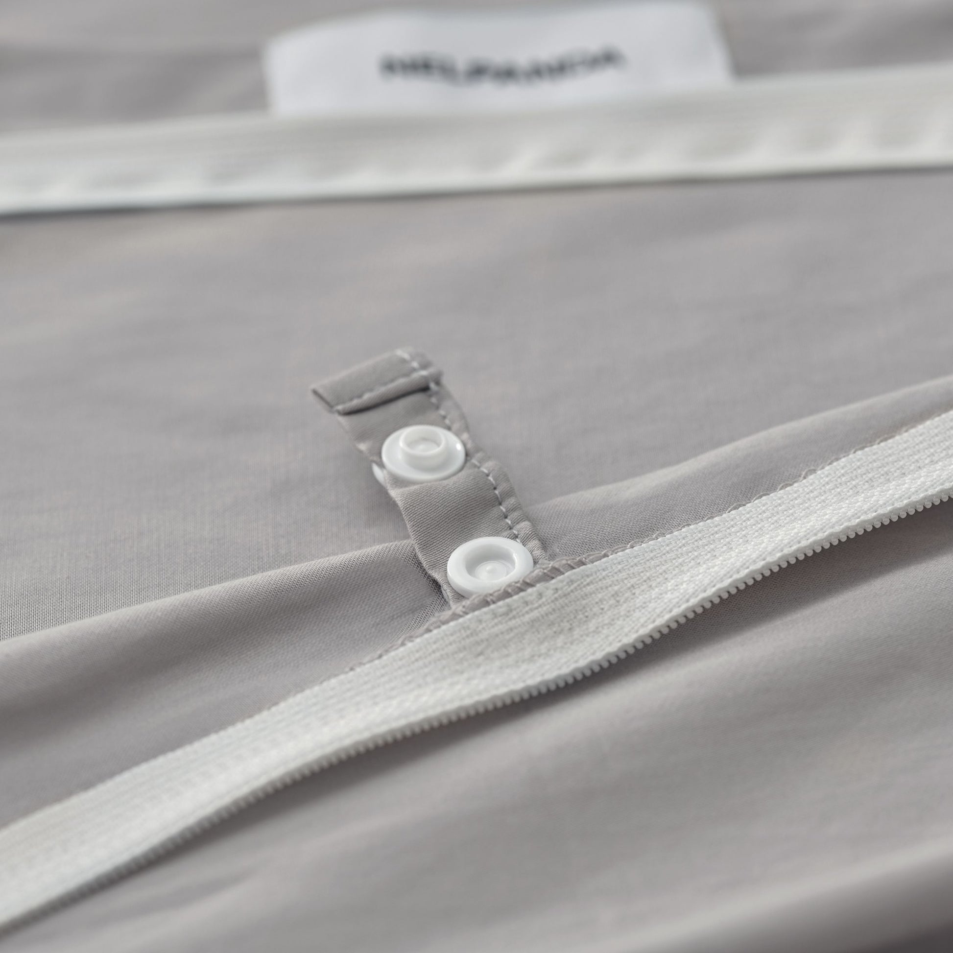 Close-up of a gray garment with a zipper and button detail