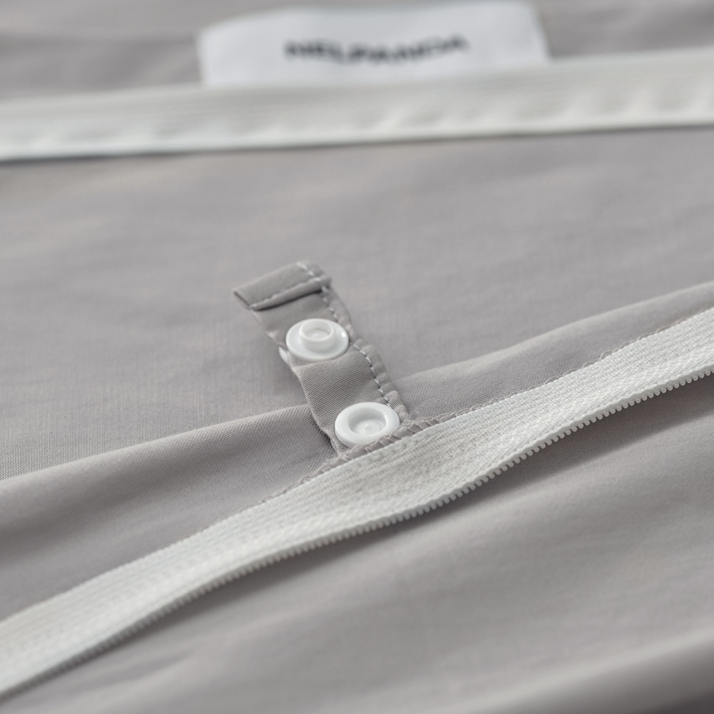 Close-up of a gray garment with a zipper and button detail