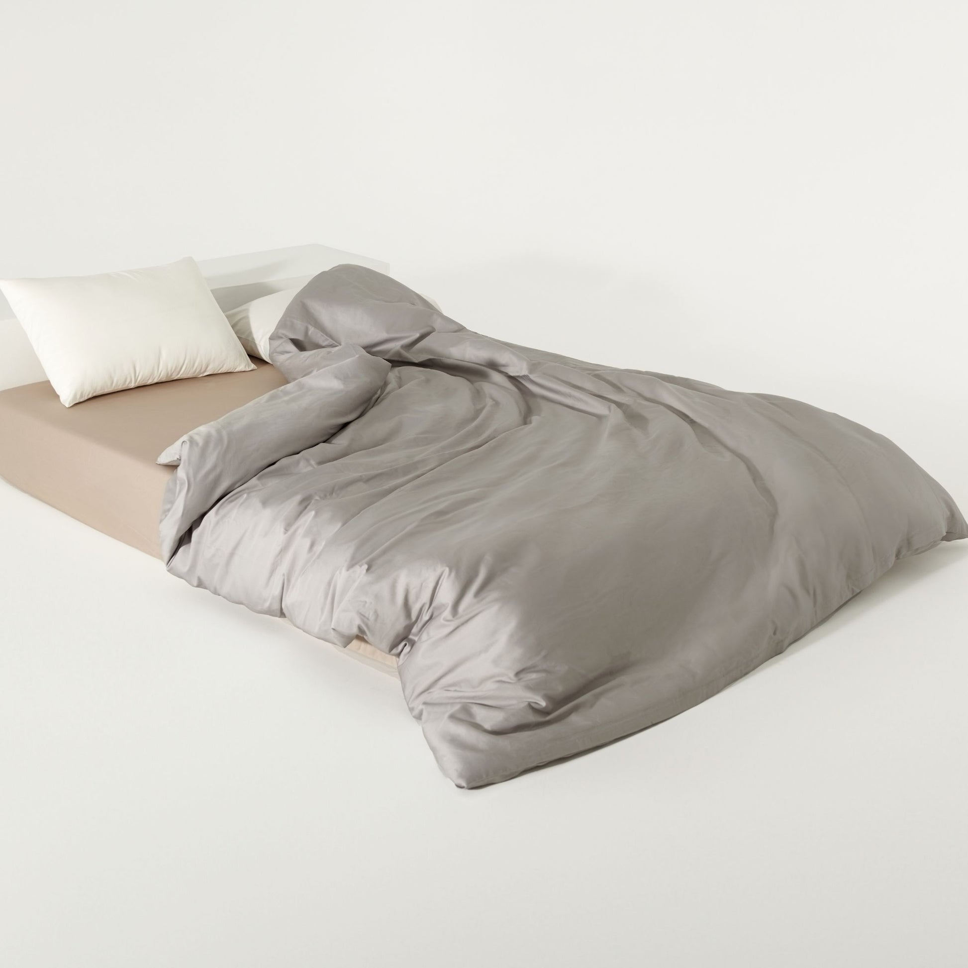 Gray duvet cover on a bed with white pillows and beige fitted sheet