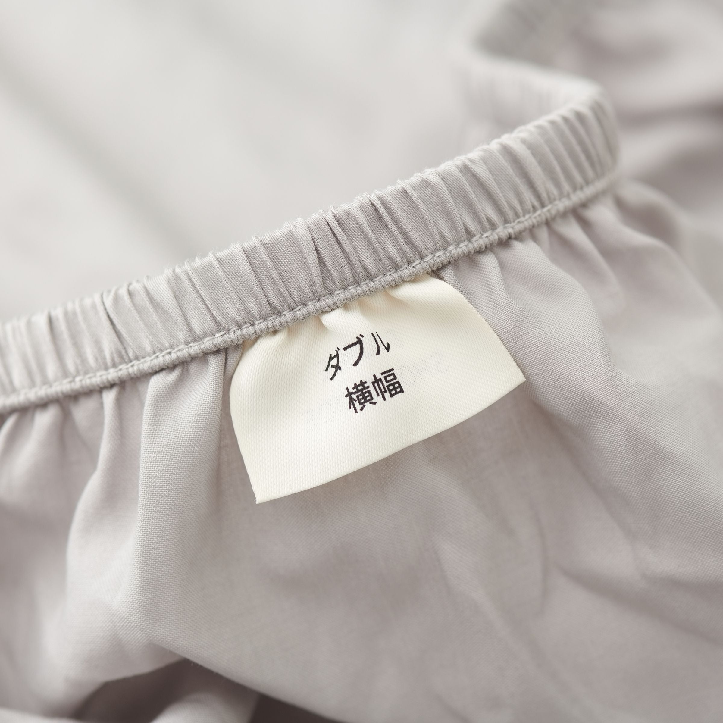 Close-up of light gray cotton fabric with a label